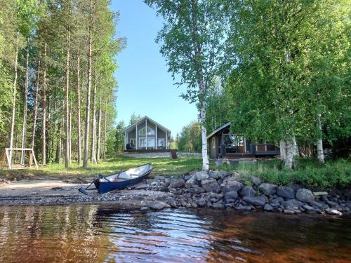 un barco a orillas de un río con una casa en Hanhi Linna en Taivalkoski