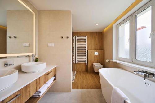 ein Badezimmer mit zwei Waschbecken, einer Badewanne und einem WC in der Unterkunft Halo Toruń in Toruń