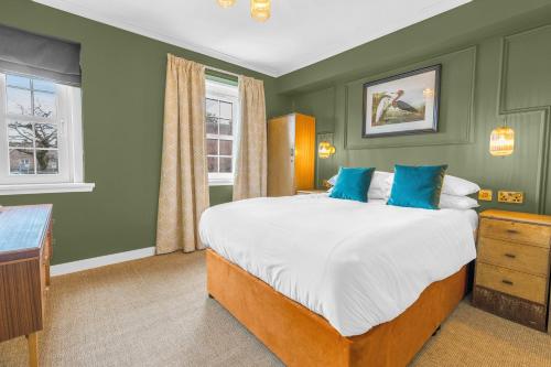 a bedroom with a large bed with blue pillows at The Alyth Hotel in Alyth
