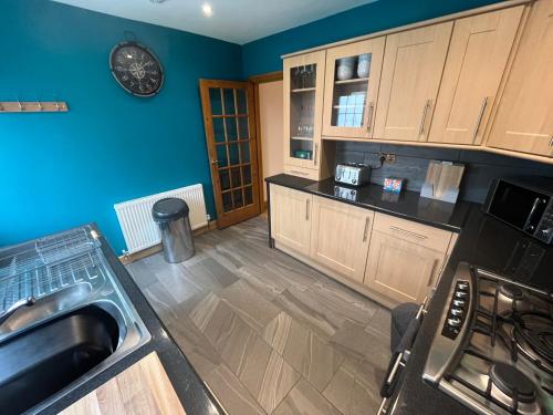 a kitchen with blue walls and wooden cabinets and a sink at Wilford Charm Spacious 3BR Retreat in Nottingham in Nottingham