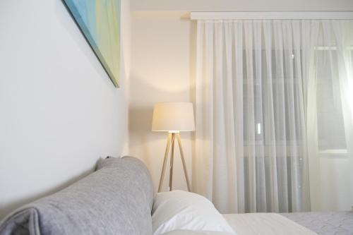 a bedroom with a bed and a lamp and a window at STAY-FIVE rooms & apartments in Shkodër