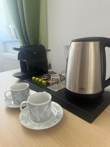 a tea kettle and two cups and saucers on a counter at Bluestone Appartements - 23qm free and near parking in Blaustein