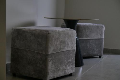 a table and two ottomans next to a table and chairs at STAY-FIVE rooms & apartments in Shkodër