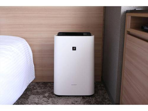 a small white refrigerator sitting next to a bed at Almont Hotel Sendai in Sendai