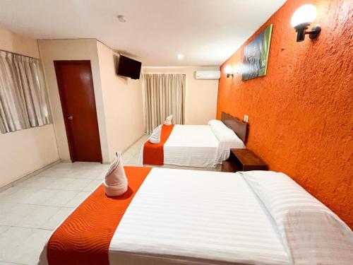 a hotel room with two beds and a television at Hotel Uxulkah in Campeche