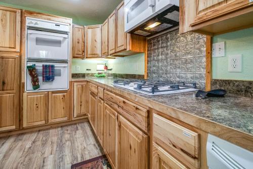 a kitchen with wooden cabinets and a stove top oven at Cotter Home with Deck about 1 Mi to Big Spring Park! in Cotter