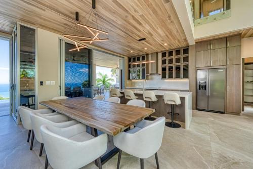 an open kitchen and dining room with a wooden table and white chairs at Villas by Tekoa in Uvita