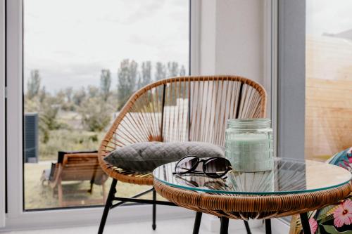 a rattan chair with a glass table and glasses on it at Apartment Fratello in Šoporňa