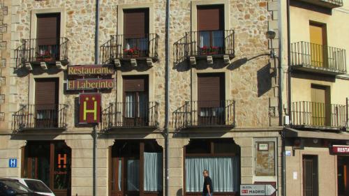 a person walking in front of a building with balconies at Hotel Laberinto in Sigüenza