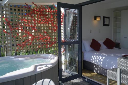 a room with a tub and a bed and a window at Palm Beach Perfection SPA Pool Free WIFI in Palm Beach