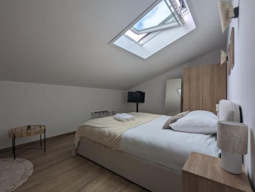 une chambre avec un lit et une lucarne dans l'établissement L'élégant 152 proche aéroport lyon, à Colombier-Saugnieu