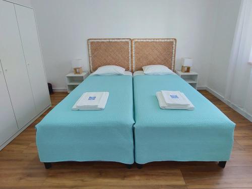 a bedroom with two blue beds and two tables at A Casa dos Azulejos in Santiago do Cacém