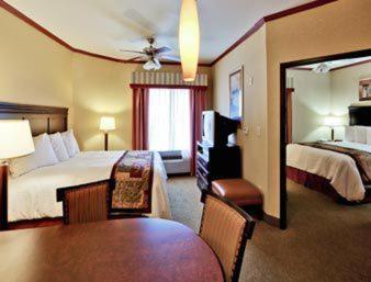 コーパスクリスティにあるHawthorn Extended Stay by Wyndham Corpus Christi Padre Isleのベッドとダイニングルームがあるホテルの部屋
