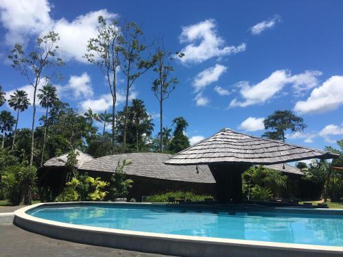 a pool with an umbrella next to a house at Houttuyn Wellness River Resort in Paramaribo