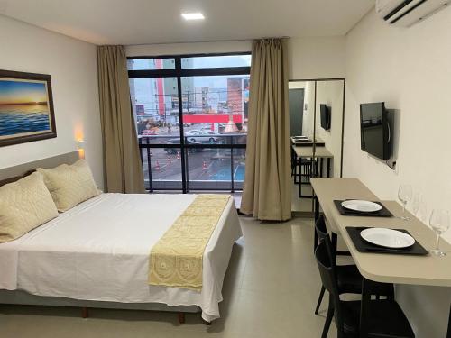 a hotel room with a bed and a desk and a window at Apartamento próximo a praia no Tramonto bessa in João Pessoa