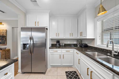 a kitchen with white cabinets and a stainless steel refrigerator at The Queen’s Gambit II in Houston