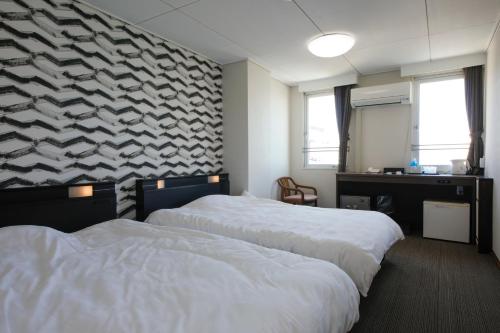 two beds in a hotel room with a wall with at Hotel Tango Nakamura So in Miyazu