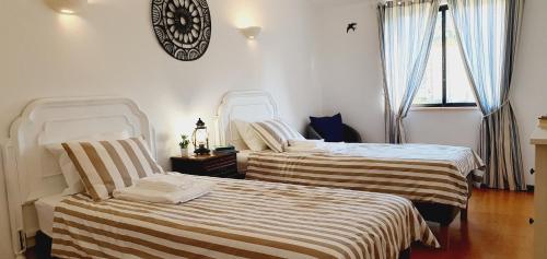 two beds in a room with a clock on the wall at Villa charmosa V2 junto à praia e à Marina de Vilamoura in Quarteira