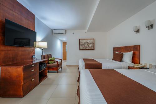 a hotel room with two beds and a flat screen tv at Hotel La Venta Inn Villahermosa in Villahermosa