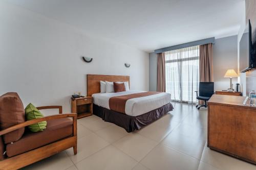 a hotel room with a bed and a chair at Hotel La Venta Inn Villahermosa in Villahermosa