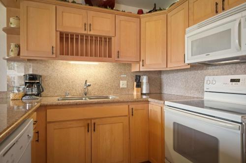 a kitchen with wooden cabinets and a sink at Aston At Poipu Kai in Koloa