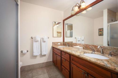 a bathroom with two sinks and a large mirror at Aston At Poipu Kai in Koloa