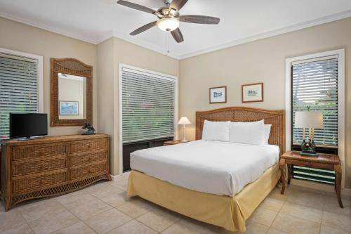 a bedroom with a bed and a tv and windows at Aston At Poipu Kai in Koloa