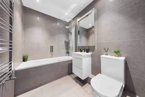 a bathroom with a toilet and a sink and a tub at Wimbledon Two Bedroom Luxury Stays - Central London in London