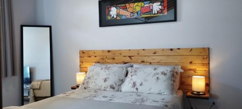 a bedroom with a bed with a wooden headboard and two lamps at Conforto e Privacidade no Roteiro do Vinho in São Roque