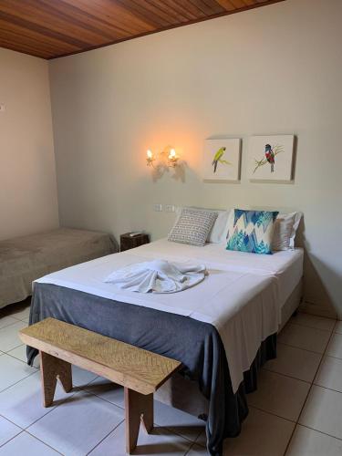 a bedroom with a large bed and a bench at Cheiro de Mato Pousada in Bonito
