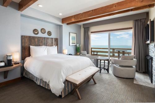 Un dormitorio con una cama grande y vista al mar. en Cypress Inn on Miramar Beach, en Half Moon Bay