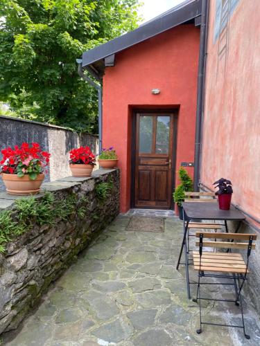 a red house with a table and a wooden door at La Casa Rosa di Riso Amaro in Orta San Giulio