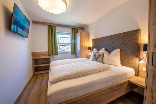 um quarto com uma cama grande e uma televisão em AppartMO - Zillertal Arena, Hohe Tauern, Salzburgerland, Krimml, Hochkrimml em Krimml
