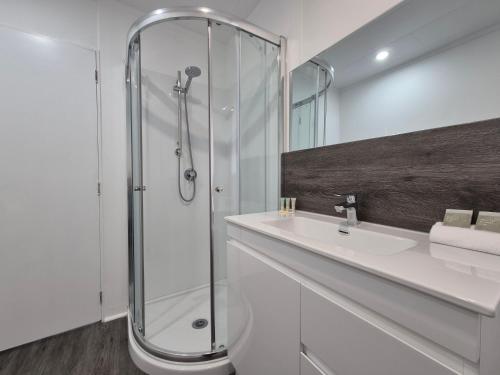 baño blanco con ducha y lavamanos en Magnolia Court Motel en Opotiki