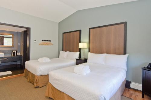 a hotel room with two beds and a bathroom at Centro Motel in Calgary