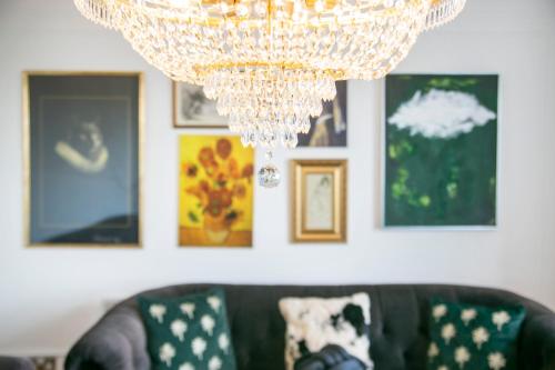 a chandelier hanging over a couch in a room with pictures at Bohemian Raphsody Apartment ✪ Grampian Lettings Ltd in Aberdeen