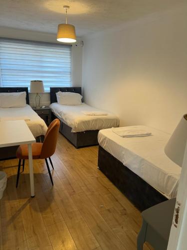 a room with two beds and a table and a chair at Beautiful 4 bedroom home 3 bathrooms, Excellent location, Family, Group, Corporate, Contractor in Thamesmead