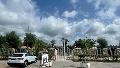 a white car parked in a parking lot with a gate at Soleada Club in Campofelice di Roccella