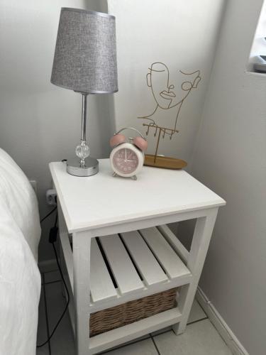 a bedside table with a lamp and a alarm clock at The Silhouette in Paarl