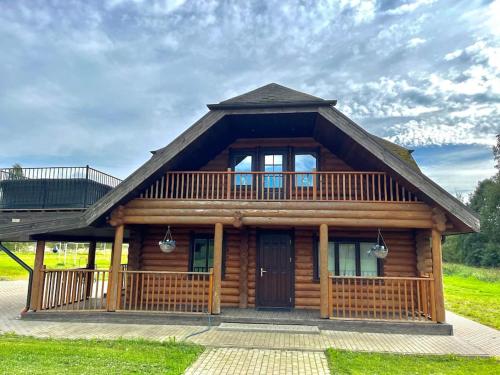 a log cabin with a porch and a balcony at Beautiful log cabin Druviņas in Limbaži