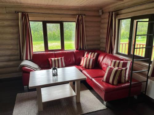 a living room with a red couch and a coffee table at Beautiful log cabin Druviņas in Limbaži