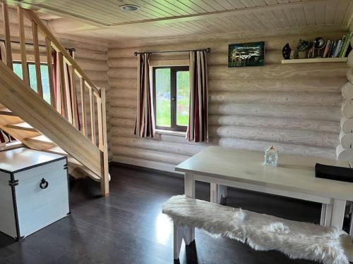 a room with a table and stairs in a log cabin at Beautiful log cabin Druviņas in Limbaži
