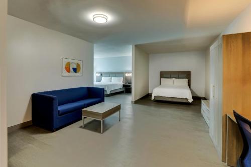 a living room with a blue couch and a bed at Holiday Inn Express Hotel & Suites Richmond by IHG in Richmond
