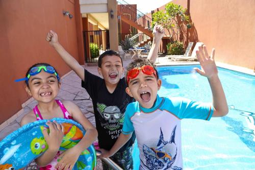 Tres jóvenes posan frente a una piscina. en Hotel Plaza las Quintas, en Hermosillo