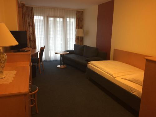 a hotel room with a bed and a couch at Hotel Görres in Wachtberg