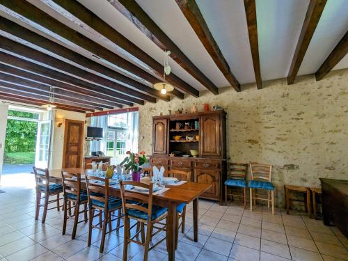 une salle à manger avec une table et des chaises en bois dans l'établissement Ancienne ferme rénovée avec jardin clos et vélos, au cœur de la Vallée Noire en Berry - FR-1-591-135, à Tranzault