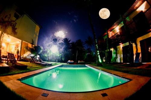 a swimming pool at night with a full moon at Villa Albergaria in Flecheiras