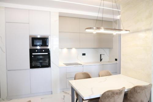 a kitchen with white cabinets and a table and chairs at Merxhan`S Apartment in Golem