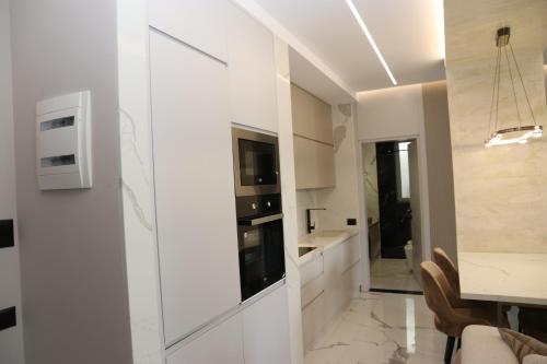 a kitchen with white cabinets and a dining room at Merxhan`S Apartment in Golem