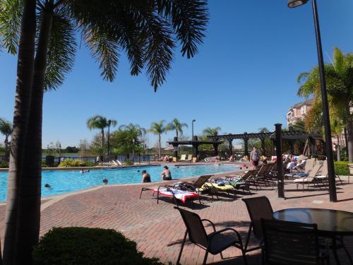 a swimming pool with chairs and people in the water at Universal Studios Area Apartment in Orlando